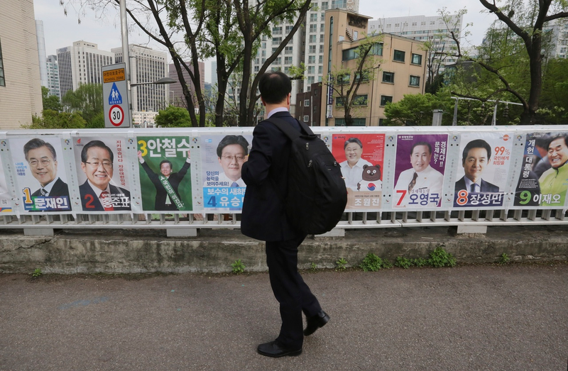 A man in Seoul, South Korea looks at posters showing candidates for presidential election on April 20, 2017 (AP Photo/Ahn Young-joon)